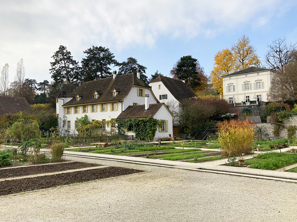 In the foreground: the cottage garden; in the background: historical buildings, the mill (Mill Museum); above: the Villa Merian, built by Alexander Löffel (1662–1736) and used as a stately home by the Merians.